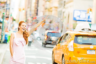 A happy woman hailing a yellow taxi while walking on a street in New York city Stock Photo