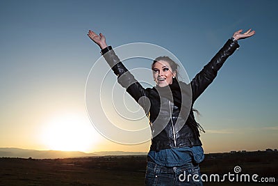 Happy woman with hand in the air celebrating in the dawn Stock Photo