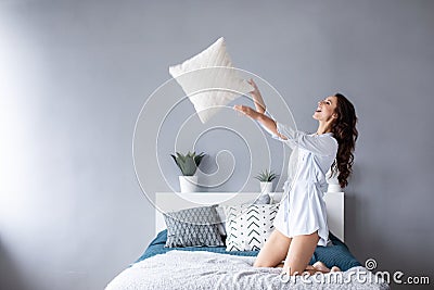 Happy woman having fun pillow throws enjoying funny activity on weekend at home Stock Photo