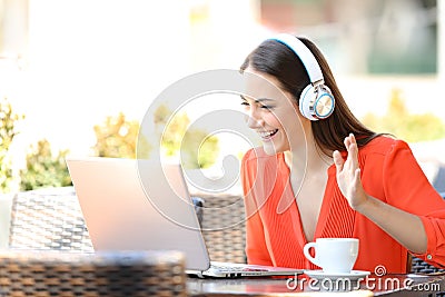 Happy woman having a video call with a laptop in a bar Stock Photo
