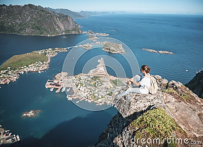 Happy woman hiker enjoying scenic view at the top of Reinebringen hike above Reine village in the Lofoten archipelago, travel to Stock Photo
