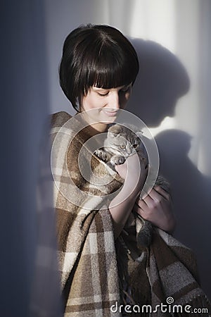 Happy Woman Holding Kitten Against Wall Stock Photo