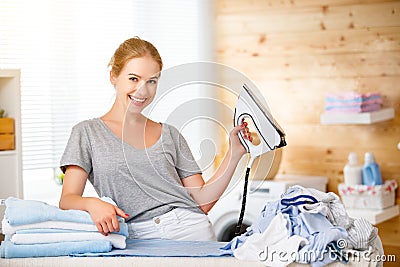 Happy woman housewife ironing clothes in laundry at home Stock Photo