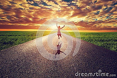 Happy woman jumping on long straight road, way towards sunset sun Stock Photo