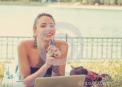 Happy woman with laptop computer and mobile phone relaxing in a park Stock Photo