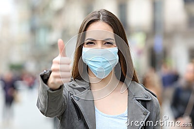 Happy woman with mask gesturing thumbs up Stock Photo