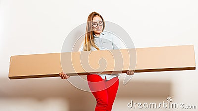 Happy woman moving into apartment carrying box. Stock Photo