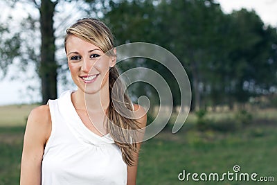 Happy woman posing in the field on a background of trees Stock Photo