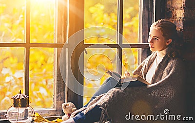 Happy woman reading book by autumn window Stock Photo