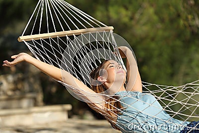 Happy woman relaxing on a hammock on holidays and raising arms Stock Photo