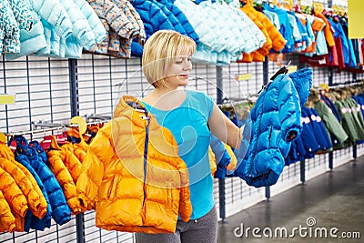 Happy woman shopping for baby jacket in shop Stock Photo