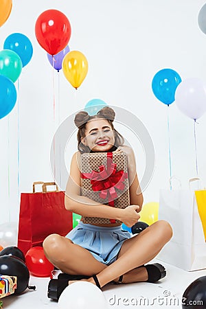 Happy woman sits in lotus position holding big gift box Stock Photo