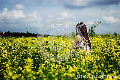 Happy woman sitting on yellow sunny flowers field Stock Photo