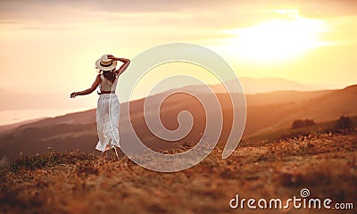 Happy woman standing with her back on sunset in nature iwith open hands Stock Photo