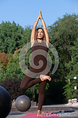 Happy woman standing in yoga pose on the grass in the park Stock Photo