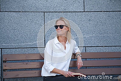 Happy woman in sunglasses sitting with book Stock Photo