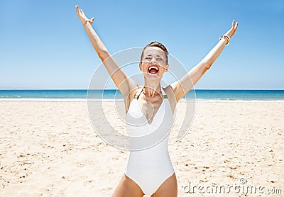 Happy woman in swimsuit at sandy beach on sunny day rejoicing Stock Photo