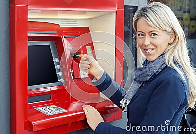 Happy woman using ATM to withdraw money Stock Photo