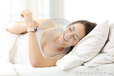 Happy woman using a smartwatch on the bed Stock Photo