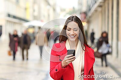 Happy woman walking using a cellphone in the street Stock Photo