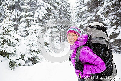 Happy woman walking in winter forest with backpack Stock Photo