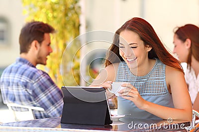 Happy woman watching videos in a tablet in a coffee shop Stock Photo