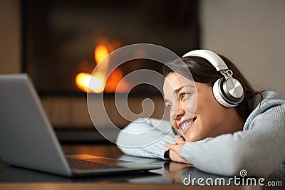 Happy woman wathing media on laptop near a fireplace Stock Photo