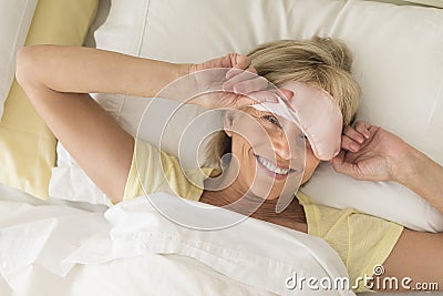 Happy Woman Wearing Sleep Mask On Bed Stock Photo