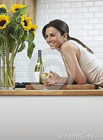 Happy Woman With Wineglass Leaning On Counter Stock Photo