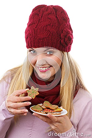 Happy woman in woolen cap and shawl eating gingerbread cookies, white background, christmas time Stock Photo