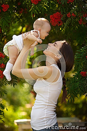 Happy woman holding in arm a baby in a garden. Happy family. Stock Photo