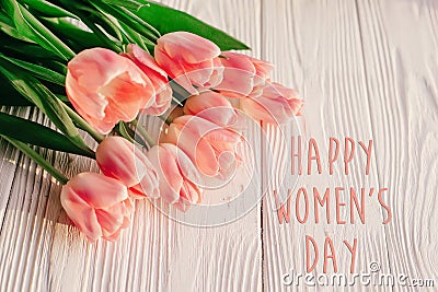 Happy women`s day text on pink tulips on white rustic wooden bac Stock Photo