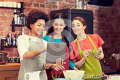 Happy women with tablet pc cooking in kitchen Stock Photo