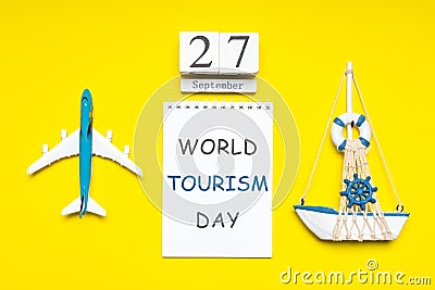 Happy world tourism day. Touristic decorative items, plane and vessel on bright yellow background. Flat lay, top view. Calendar Stock Photo