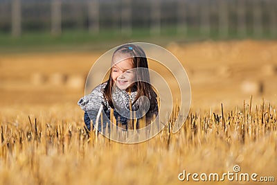 Happy two year old girl walking in a summer harvested field Stock Photo