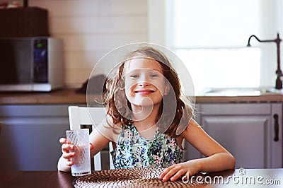 Happy 8 years old child girl having breakfast in country kitchen, drinking milk Stock Photo