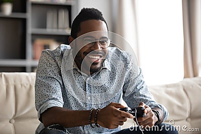 Happy young african guy holding joystick controller playing video game Stock Photo