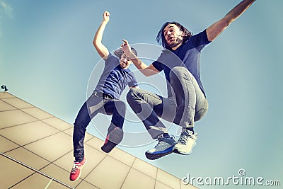 Happy young adults jumping on a terrace Stock Photo