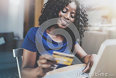 Happy young african american woman shopping online through laptop using credit card at home. Horizontal,blurred Stock Photo