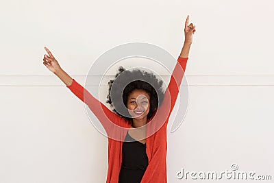 Happy young african woman with arms raised by white wall Stock Photo