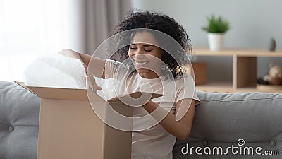 Happy african woman satisfied customer open parcel sit on sofa Stock Photo