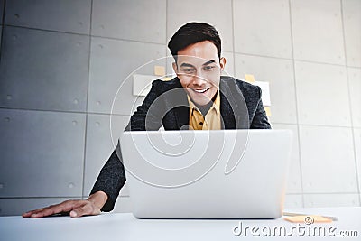 Happy Young Asian Businessman Working on Computer Laptop in Office. Stock Photo