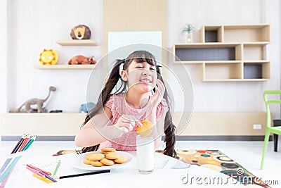 happy young asian girl eat milk cookie biscuit with dairy fresh milk for breakfast in morning after finish homework from school Stock Photo