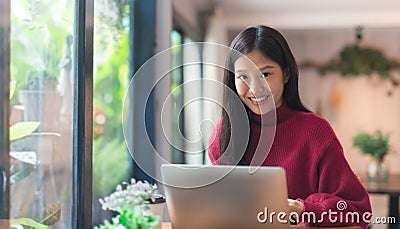 Happy young Asian girl working at a coffee shop with a laptop .Woman happy smiling to camera in cafe day. Stock Photo