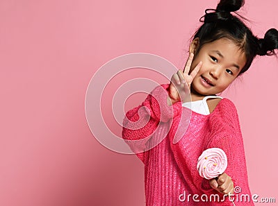 Happy young asian little girl kid lick eat happy big sweet lollypop candy on pink Stock Photo