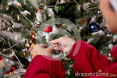 Happy young asian woman smiling hanging decorating ornament on Christmas tree in the living room at home. Stock Photo