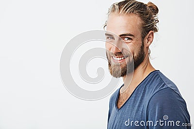 Happy young bearded guy with fashionable hairstyle and beard looking at camera, brightfully smiling with teeth, being Stock Photo