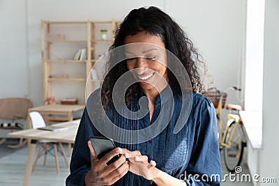 Happy young biracial business woman holding smartphone, looking at screen. Stock Photo