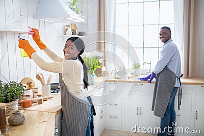 Happy young black couple cleaning their kitchen together, copy space. Housecleaning service concept Stock Photo