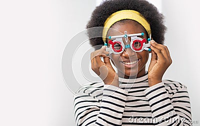Happy Young black woman checking vision with eye test glasses during a medical examination at the ophthalmological office, Stock Photo